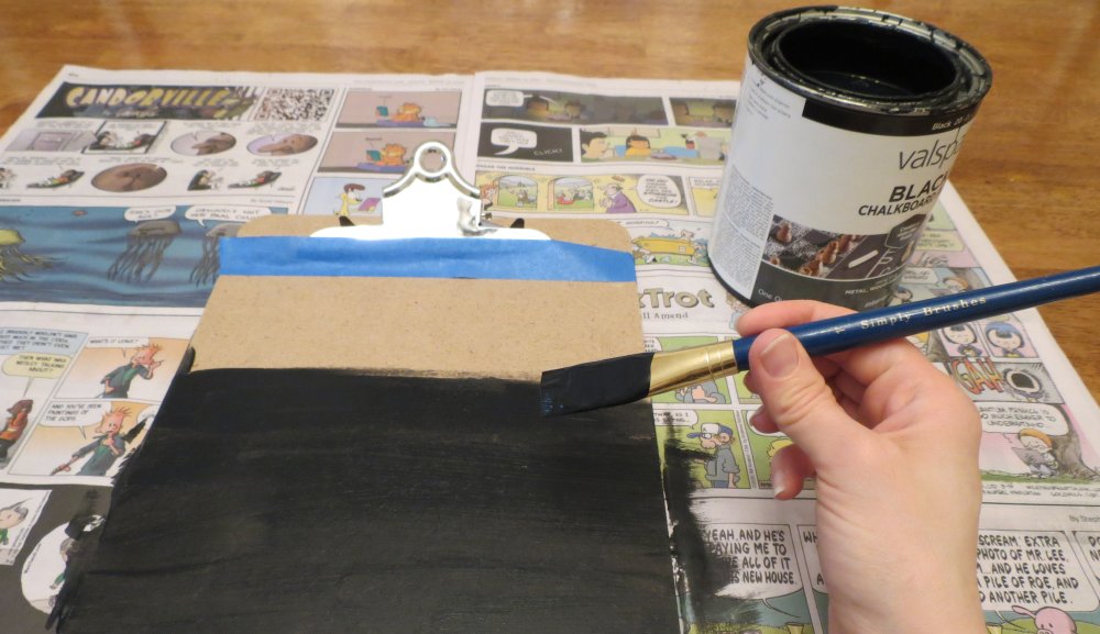 2. Open the chalkboard paint and mix according to paint instructions. Paint the clipboard below the tape, moving in the same direction to create a smooth surface. (You can apply a second paint coat, if you like.) Wash the paintbrush in a sink. After 10 minutes, gently reposition the clipboard on the newspaper to avoid any sticking. Let it dry for 24 hours. (Photo for The Washington Post by Kris Coronado)