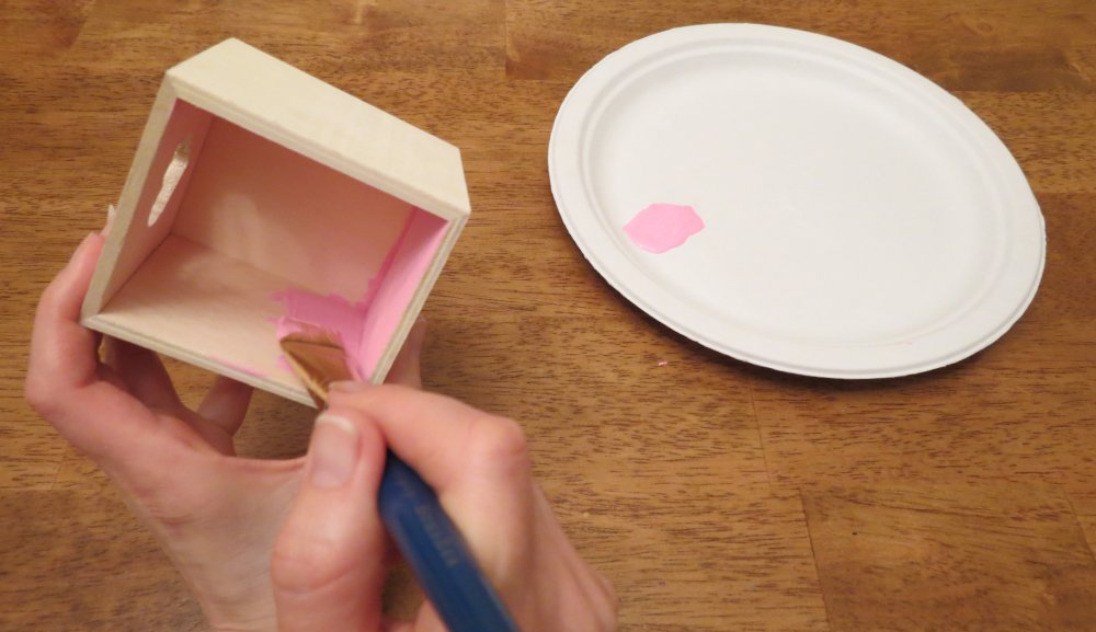 3. As the clipboard dries, squirt a quarter-size amount of one acrylic paint color on the paper plate. Use this color to paint the inside of the wooden box, using more paint as needed. When the inside is finished, rinse the paintbrush and paint the outside with the second color. Place the box on the newspaper to dry for five minutes. (Photo for The Washington Post by Kris Coronado)