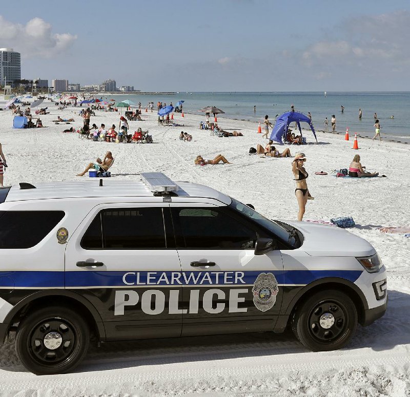Police officers patrol the area after Clearwater Beach officially reopened to the public Monday in Clearwater Beach, Fla. More photos at arkansasonline.com/55virus/. (AP/Chris O’Meara) 