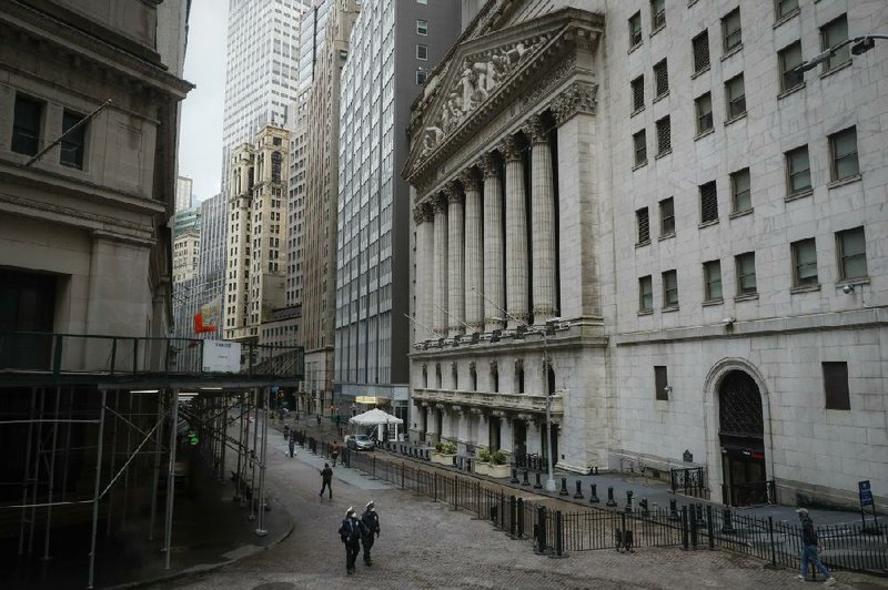 New York Police Department officers walk along a mostly deserted Wall Street. (AP/John Minchillo) 