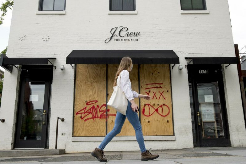 A woman walks past a boarded-up J. Crew storefront in Washington last week. (AP/Andrew Harnik) 
