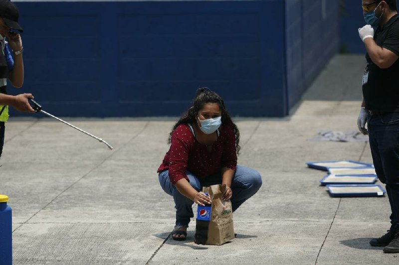 Deported Guatemalan Vanessa Diaz looks toward her family last month as she picks up the food they delivered to the site in Guatemala City where those who are returned from the U.S. are held in quarantine for two weeks. (AP/Moises Castillo) 