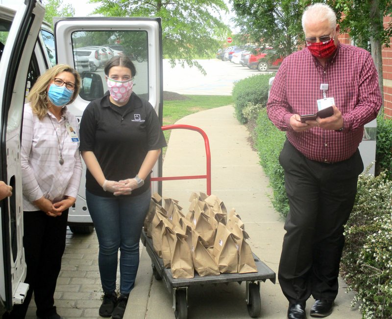 Marc Hayot/Herald Leader Maria Wleklinski, chief nursing officer (left); Sarah Murphy, manager for Event Group Catering; and Scott Harris, materials management director pose for a photo with meals delivered by Event Group Catering through donations made by the Arkansas Philharmonic Orchestra. The orchestra's patrons donated $9 per meal for those who work at various healthcare facilities, one of which is Siloam Springs Regional Hospital.