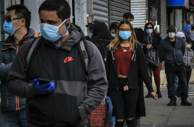 People wear masks and maintain social distance Tuesday while wait- ing in line outside a store in the Brooklyn borough of New York. (AP/Bebeto Matthews) 