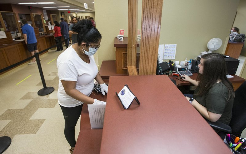 Anna Alvarenga (left) of Bethel Heights gets help Thursday from deputy collector Marissa Lunde at the Bentonville revenue office. Go to nwaonline.com/200508Daily/ to see more photos. (NWA Democrat-Gazette/Ben Goff)