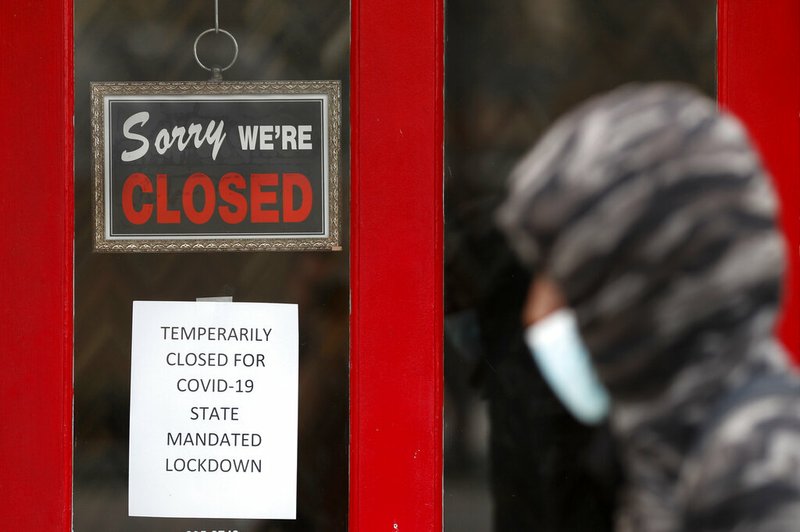 FILE - In this May 7, 2020, file photo, a pedestrian walks by The Framing Gallery, closed due to the COVID-19 pandemic, in Grosse Pointe, Mich. The U.S. unemployment rate hit 14.7% in April, the highest rate since the Great Depression, as 20.5 million jobs vanished in the worst monthly loss on record. The figures are stark evidence of the damage the coronavirus has done to a now-shattered economy. (AP Photo/Paul Sancya, File)