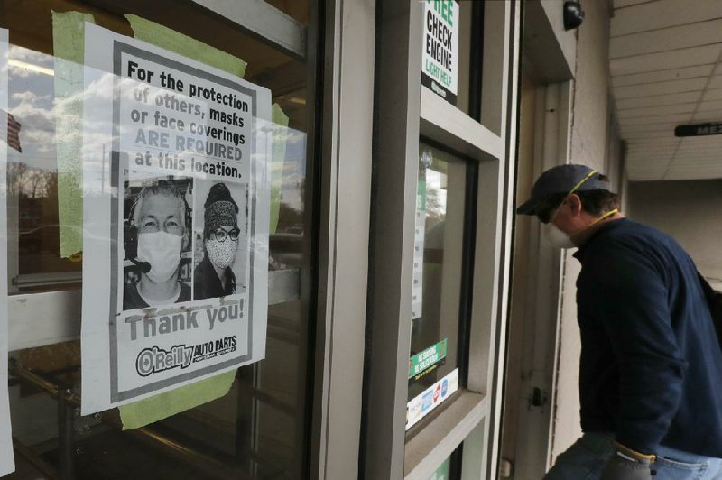 A shopper walks past a sign taped to the front door of an O’Reilly Auto Parts store Thursday in Beverly Hills, Mich. The store is requiring that customers wear masks.
(AP/Carlos Osorio)