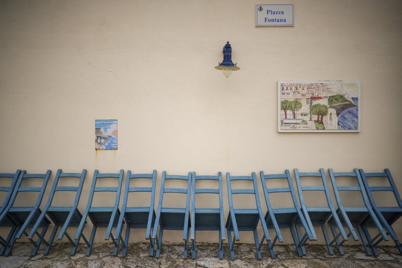 In this photo taken on Tuesday, April 28, 2020 restaurant chairs are lined up against a wall outside a closed restaurant in Sperlonga, a fashionable seaside town about 120km (80 miles) south of Rome. Normally, at this time of year Sperlonga would already be bustling with its first clients of the season. The restaurants would be fully operational and the golden-sand beaches, although still too chilly for Italians, would have been enjoyed by northern Europeans eager for some sunlight after a long, dark winter. (AP Photo/Andrew Medichini)