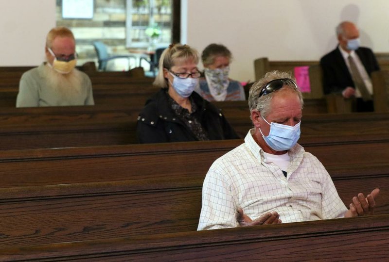 Members of Crossroads New Baptist Church pray Sunday while social distancing during the church’s first in-person service since March. Adult members were required to wear masks during the service. More photos at www.arkansasonline.com/511church/. (Arkansas Democrat-Gazette/Thomas Metthe) 