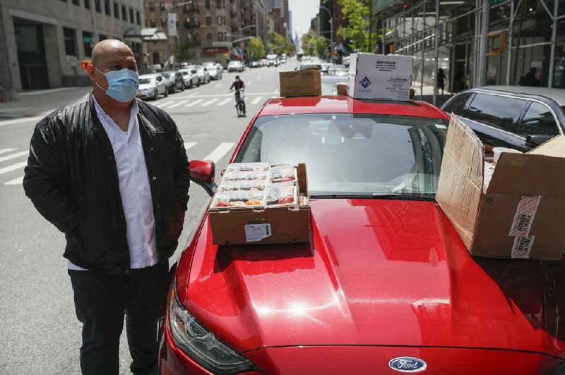 Kissaki chef Mark Garcia waits to drop off sushi meals from his rental car for delivery to New York City’s Mt. Sinai Medical Center that were purchased with donated funds to feed medical workers combating the coronavirus pandemic. The executive chef at Kissaki in Manhattan has been delivering bluefin tuna, yellowtail and uni to hospital workers using a car rented by restaurant owner Garry Kanfer.
(AP Photo/John Minchillo)