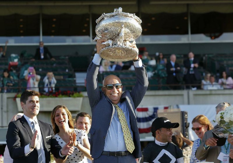 Mark Casse, here holding up the winner’s trophy after Sir Winston won the Belmont Stakes last June, said the traditions of the sport are “the least of our concerns right now” as coronavirus pandemic complicates this year’s races. (AP/Eduardo Munoz Alvarez) 