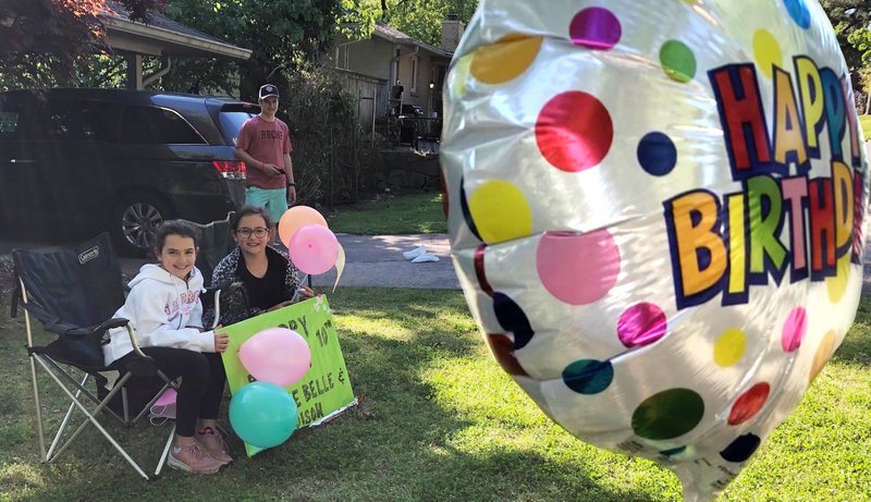 Ten-year-old twins Charlie Belle and Addison Cole enjoy their front yard birthday party April 4 as "guests" motor past to drop off gifts and honk. (Democrat-Gazette photo illustration/Celia Storey)