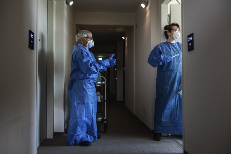 In this photo provided by the Alfred-Wegener-Institut and taken on May 6, 2020, Anna-Lena Bohlen, right and Eberhard Kolhberg enter the room of a MOSAiC scientist to take a coronavirus test, in Bremerhaven, Germany. They prepared for icy cold and trained to watch for polar bears, but a pandemic just wasn't part of the program. Now dozens of scientists are sitting in quarantine, waiting for permission to sail forth and capture a crucial moment in the polar calendar that's essential to their year-long Arctic research mission. (Alfred-Wegener-Institut via AP)