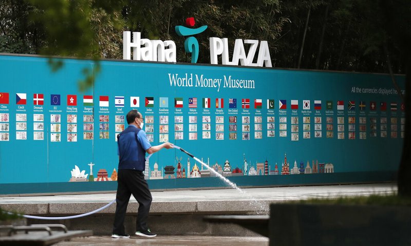 A worker cleans near a bank's currency advertisement board in Seoul, South Korea, Tuesday, May 12, 2020.