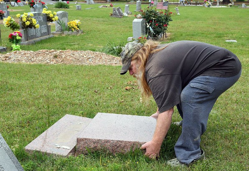 Robert Burks attempts to lift a headstone Monday after it was knocked down when Cutter Morning Star Cemetery in Hot Springs was vandalized over the weekend. (The Sentinel-Record/Grace Brown) 
