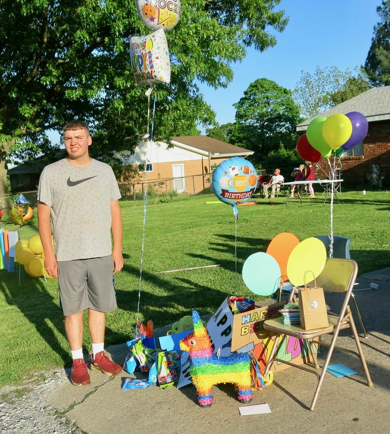 Westside Eagle Observer/SUSAN HOLLAND Taylor Crose poses beside a pile of gifts, cards and balloon bouquets he received during his 16th birthday parade. Seventy-seven vehicles participated in the parade organized by his mother as a surprise to make this birthday extra special.