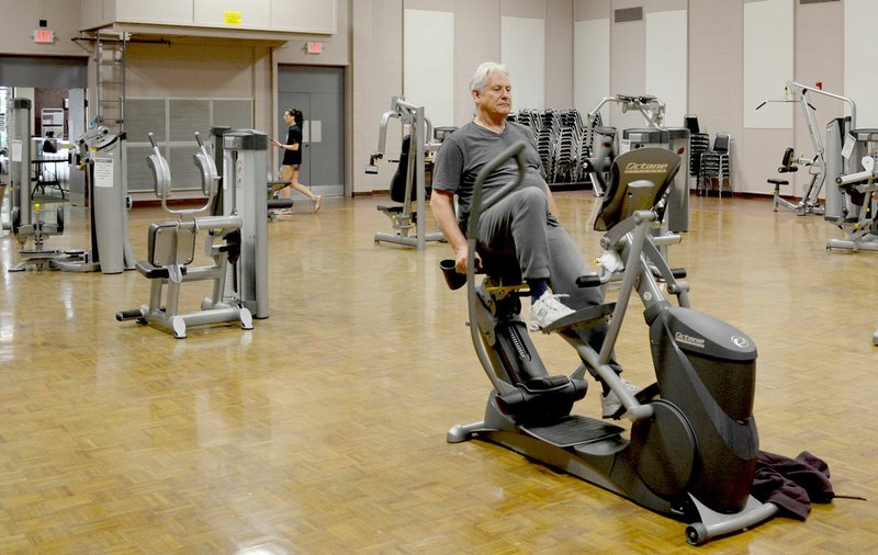 Keith Bryant/The Weekly Vista Bella Vista resident Jeff Graf pedals on a stationary bike in the Riordan Hall auditorium. Equipment was moved to the auditorium to allow adequate spacing per Arkansas Department of Health guidelines.