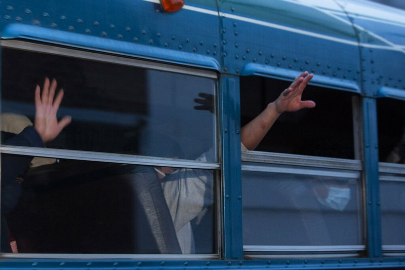 FILE - In this May 4, 2020, file photo, Guatemalans deported from the U.S., wave from a bus after arriving at La Aurora airport in Guatemala City.