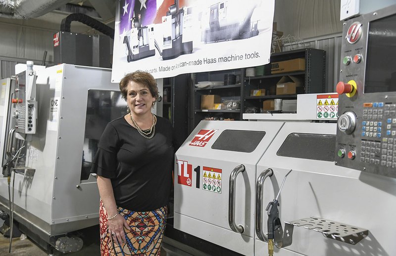 Kelli Embry, VP for Workforce at National Park College has her photo taken at the National Park College's Innovative Technologies Center near the industrial equipment she helped secure through a grant she wrote. - Photo by Grace Brown of The Sentinel-Record