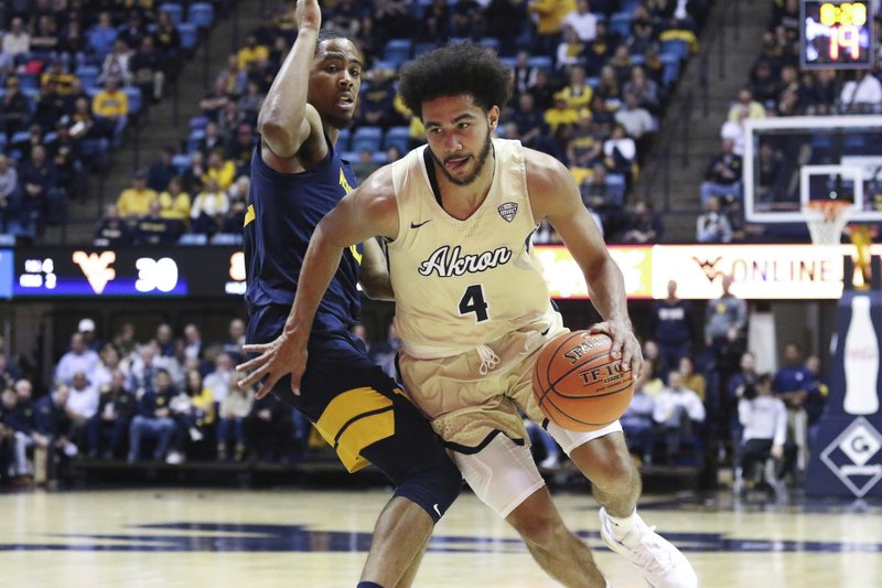  In this Nov. 8, 2019, file photo, Akron's Tyler Cheese is defended by West Virginia's Taz Sherman during an NCAA college basketball game in Morgantown, W.Va. Akron is dropping men's golf and cross country and women's tennis in cost-cutting moves due to the COVID-19 pandemic. The school said the reduction will take effect at the end of the 2019-20 academic year. (AP Photo/Kathleen Batten, File)