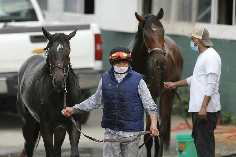 An exercise rider walks with a horse after its bath after a workout Friday at Pimlico Race Course in Baltimore. Pimlico and many tracks across North America remain dark because of the coronavirus pandemic.
(AP/Julio Cortez)