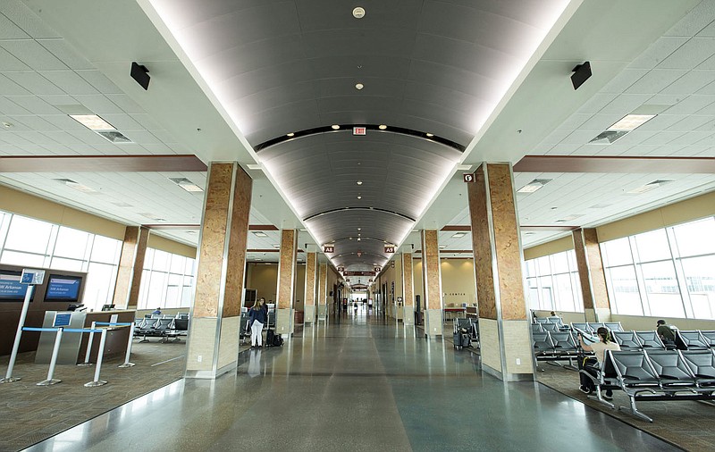 Passengers wait for a departing flight Wednesday in a mostly empty concourse at Northwest Arkansas National Airport in Highfill. Go to nwaonline.com/200517Daily/ to see more photos. (NWA Democrat-Gazette/Ben Goff)