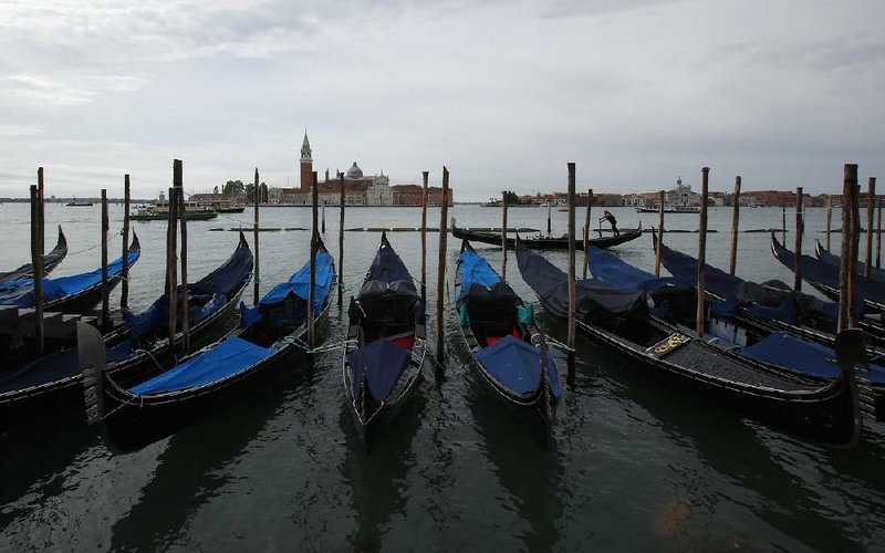 Gondolas sit unused Wednesday at the Grand Canal in Venice, Italy. The disruption in the city’s tourism industry is giving leaders a chance to consider restoring the traditional ways of Venetian life. More photos at arkansasonline.com/517venice/.
(AP/Antonio Calanni)