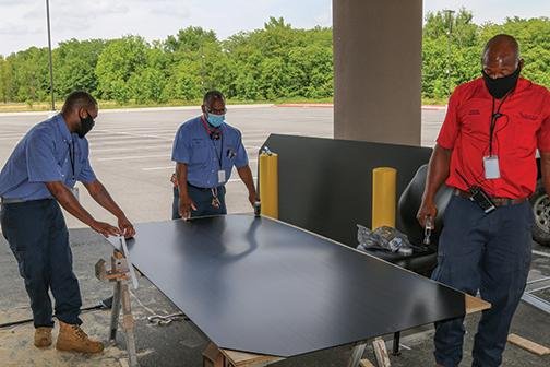 Saracen Development employees (from left) DaCarlos Spears, Carl Jones and James Thomas construct a partition to be placed be- tween the Saracen casino’s slot machines and offer some protec- tion against the coronavirus. (Arkansas Democrat-Gazette/Dale Ellis) 