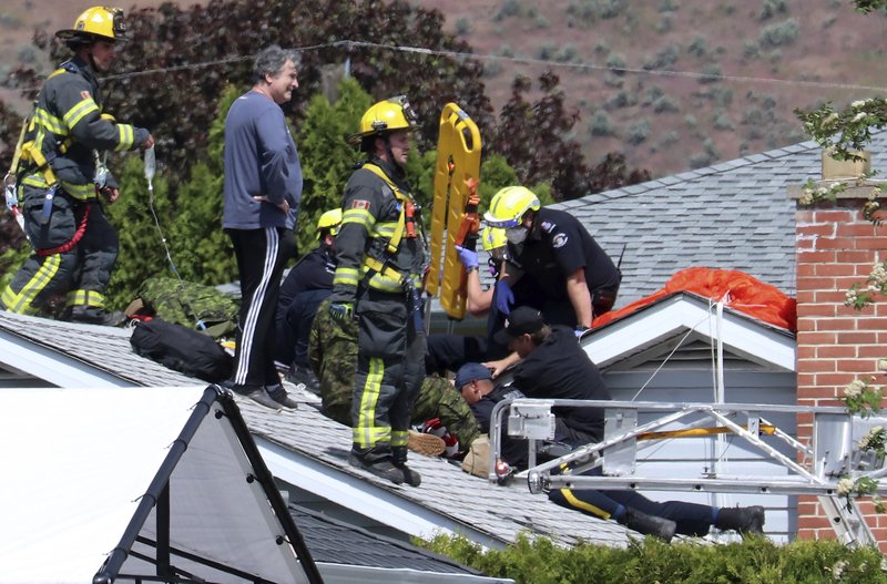 First responders attend to a person on a rooftop at the scene of a crash involving a Canadian Forces Snowbirds airplane in Kamloops, British Columbia, Sunday, May 17, 2020. (Brendan Kergin/Castanet Kamloops/The Canadian Press via AP)