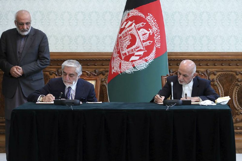 Afghan President Ashraf Ghani (right) and rival Abdullah Abdullah sign the deal Sunday at the pres- idential palace in Kabul. (AP/Afghan Presidential Palace) 
