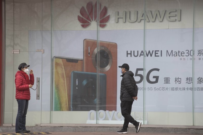 In this photo taken Sunday, March 8, 2020, residents wearing masks against the coronavirus walk past an Huawei advertisement in Beijing. China's commerce ministry says on Sunday, May 17, 2020 it will take &quot;all necessary measures&quot; in response to new U.S. restrictions on Chinese tech giant Huawei's ability to use American technology, calling the measures an abuse of state power and a violation of market principles. (AP Photo/Ng Han Guan)