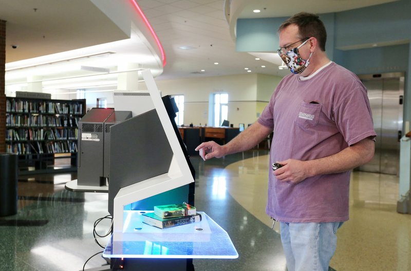 Kevin La Born uses a self check out kiosk Monday at the Fayetteville Public Library. The library opened with limited hours and social distancing restrictions for the first time since mid-March because of the covid-19 pandemic. Twenty two patrons visited the library within the first 10 minutes of opening. The library will continue to offer online catalog items for curbside pick-up. Library materials can now be returned in drive-by drop boxes. Check out nwaonline.com/200519Daily/ and nwadg.com/photos for a photo gallery.
(NWA Democrat-Gazette/David Gottschalk)