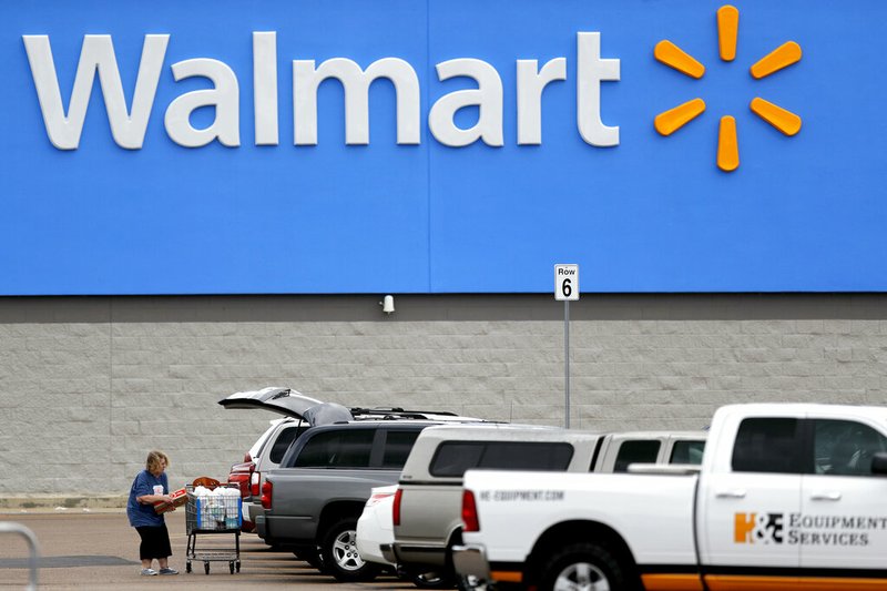 In this March 31, 2020 file photo, a woman pulls groceries from a cart to her vehicle outside of a Walmart store in Pearl, Miss. Walmart became a lifeline to millions of people as the coronavirus spread, and its profit and sales surged during the first quarter, topping almost all expectations. (AP Photo/Julio Cortez, File)