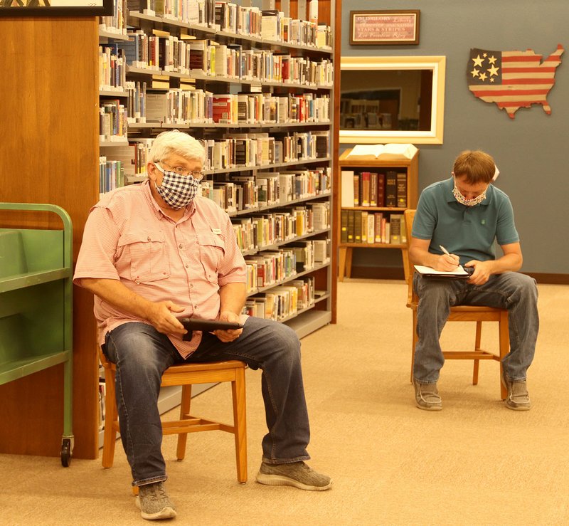 LYNN KUTTER ENTERPRISE-LEADER Prairie Grove City Council members Rick Clayton and Doug Stumbaugh attend a council meeting last week held in the middle of Prairie Grove Public Library. Those at the meeting were spaced about 6 feet apart, based on safe distancing guidelines issued by Gov. Asa Hutchinson.