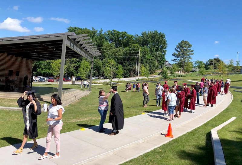 Photos submitted Students line up six feet apart in Memorial Park on Sunday for free graduation portraits in their caps and gowns by Luke Davis, owner of Main Street Photography.