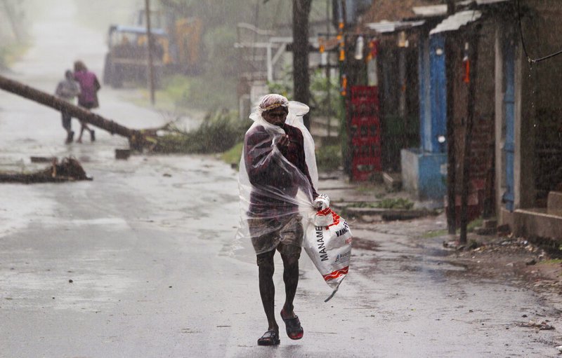 A man covers himself with a plastic sheet and walks in the rain ahead of the landfall of Cyclone Amphan in Bhadrak district, the eastern Indian state of Orissa, on Wednesday, May 20, 2020. A strong cyclone blew heavy rains and strong winds into coastal India and Bangladesh on Wednesday after more than 2.6 million people were moved to shelters in a frantic evacuation made more challenging by coronavirus.