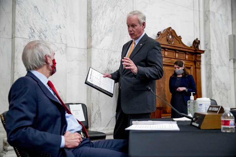 Chairman Sen. Ron Johnson, R-Wis., center, speaks with Sen. Rob Portman, R-Ohio, left, at the conclusion of a Senate Homeland Security and Governmental Affairs committee meeting on Capitol Hill in Washington, Wednesday, May 20, 2020, after voting to issue a subpoena to Blue Star Strategies.
