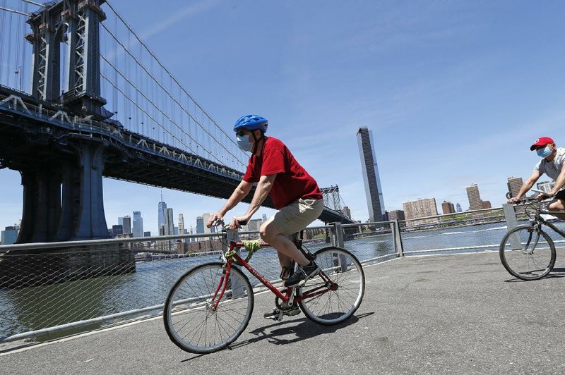 With the Manhattan Bridge as a backdrop, two bicyclists ride Sunday in Brooklyn Bridge Park in New York. (AP/Kathy Willens) 
