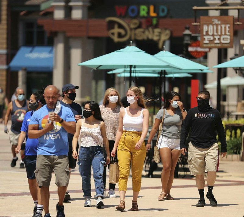 Guests stroll through Disney Springs in Orlando, Fla., on Wednesday after being screened at the entrance as the park begins a limited reopening.
(AP/Orlando Sentinel/Stephen M. Dowell)