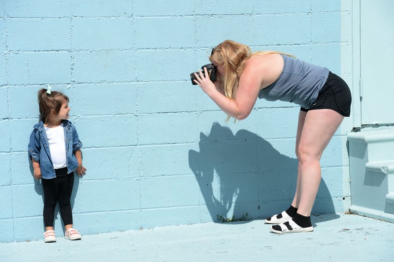 Tonia Hanson (right), owner of Tonia Hanson Photography in Fayetteville, takes a photograph Thursday of Charleston Smolinski, 3, while taking family photographs with Charleston's twin brother, Roman, and mother, Ally Smolinski of Rogers, in front of the Maude Wall at Maude Boutique in Fayetteville. The clothing store invites people to use their multicolored back wall for photographs. Go to nwaonline.com/200522Daily/ for today's photo gallery. (NWA Democrat-Gazette/Andy Shupe)