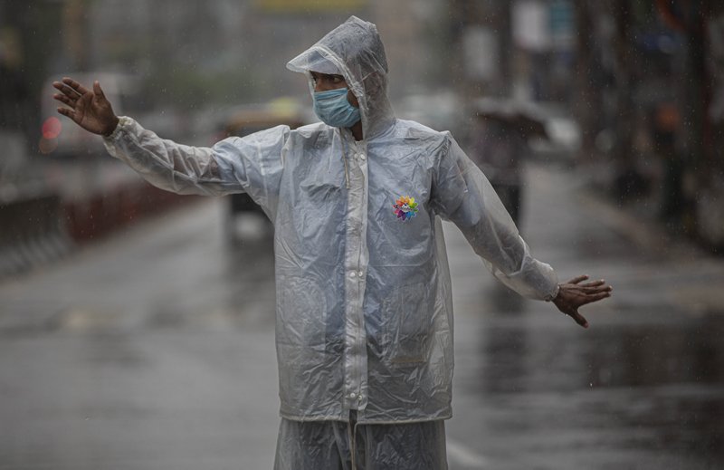 An Indian traffic police person controls traffic during heavy rain in Gauhati, India, Thursday, May 21, 2020. A powerful cyclone ripped through densely populated coastal India and Bangladesh, blowing off roofs and whipping up waves that swallowed embankments and bridges and left entire villages without access to fresh water, electricity and communications. (AP Photo/Anupam Nath)