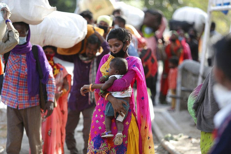 A woman holds a child and waits with other migrant workers outside a railway station hoping to be able to travel to their home states, in Jammu, India, Friday, May 22, 2020. story.lead_photo.caption