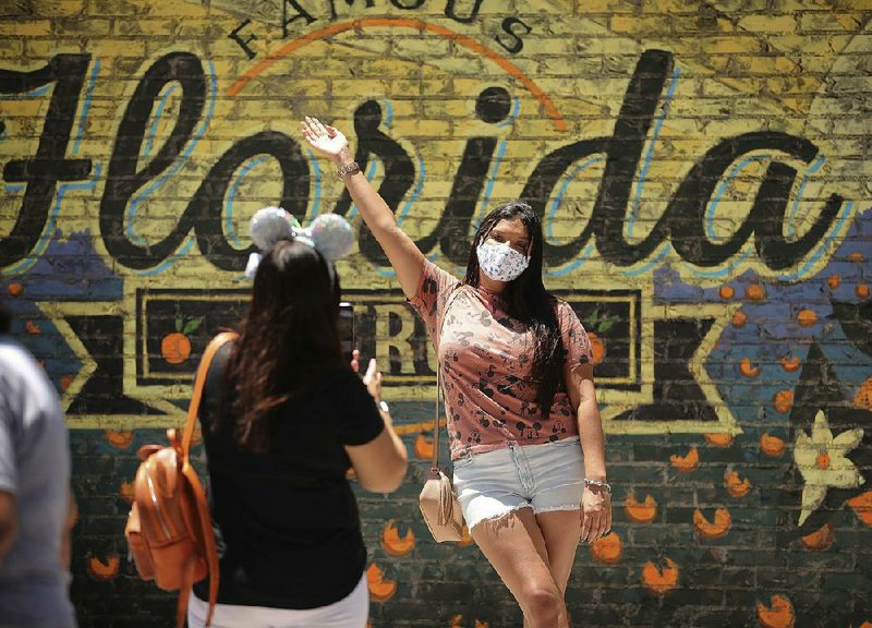Guests take pictures Wednesday, May 20, 2020, at Disney Springs in Orlando, Fla., when Walt Disney World’s shopping and dining complex held a limited reopening.
(AP/Orlando Sentinel/Stephen M. Dowell)