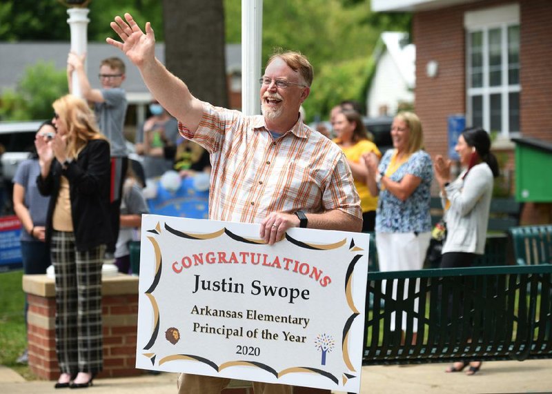 Lee Elementary School Principal Justin Swope waves to passing well-wishers Thursday from the parking lot of the school in Springdale. Swope was recognized as the Arkansas Elementary Principal of the Year by the Arkansas Association of Elementary School Principals.
(NWA Democrat-Gazette/David Gottschalk)