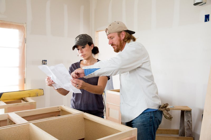 Chip and Joanna Gaines discuss cabinets while working on a home. The Gaines's home design work seems to divide along traditional gender lines, but Joanna is the driving force behind the brand. (Magnolia via The New York Times) 