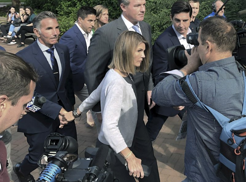 FILE - In this Aug. 27, 2019, file photo, Lori Loughlin departs federal court with her husband, clothing designer Mossimo Giannulli, left, in Boston, after a hearing in a nationwide college admissions bribery scandal. Loughlin and Giannulli have agreed to plead guilty in a video arraignment scheduled for Friday, May 22, 2020, to charges of trying to secure the fraudulent admission of their two children to the University of Southern California as purported athletic recruits. (AP Photo/Philip Marcelo, File)