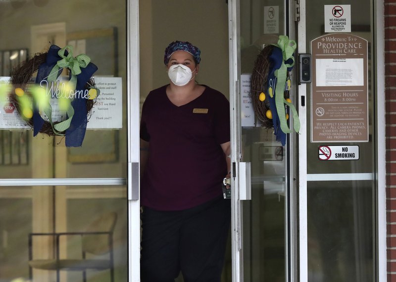 A healthcare worker looks out the main doors at Providence of Sparta Health and Rehab where more than thirty residents are infected with coronavirus on Wednesday, May 20, 2020, in Sparta. Hancock county, halfway between Augusta and Macon has become a new coronavirus hotspot. (Curtis Compton/Atlanta Journal-Constitution via AP)