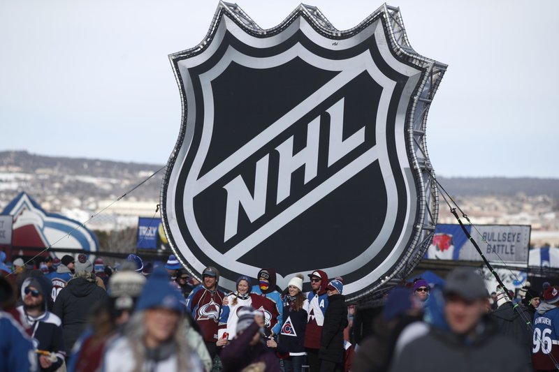 In this Saturday, Feb. 15, 2020, file photo, fans pose below the NHL league logo at a display outside Falcon Stadium before an NHL Stadium Series outdoor hockey game between the Los Angeles Kings and Colorado Avalanche, at Air Force Academy, Colo. The NHL Players' Association's executive board is voting on a 24-team playoff proposal as the return-to-play format, a person with knowledge of the situation told The Associated Press, late Thursday, May 21, 2020. (AP Photo/David Zalubowski, File) story.lead_photo.caption