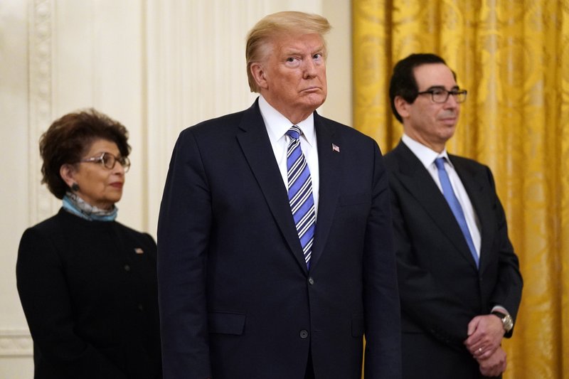 FILE - In this April 28, 2020 file photo President Donald Trump, along with Jovita Carranza, administrator of the Small Business Administration, and Treasury Secretary Steven Mnuchin listen during an event about the Paycheck Protection Program used to support small businesses during the coronavirus outbreak, in the East Room of the White House in Washington.  (AP Photo/Evan Vucci)