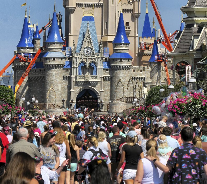 FILE - In this March 12, 2020, file photo, a crowd is shown along Main Street USA in front of Cinderella Castle in the Magic Kingdom at Walt Disney World in Lake Buena Vista, Fla. As Walt Disney World prepares to allow some third-party shops and restaurants to open at its entertainment complex later this week, it's posting a warning. While enhanced safety measures are being taken at Disney Springs, &#x201c;an inherent risk of exposure to COVID-19 exists in any public place where people are present,&quot; the company said Monday, May 18, 2020, on a website for the entertainment complex.(Joe Burbank/Orlando Sentinel via AP, FIle)